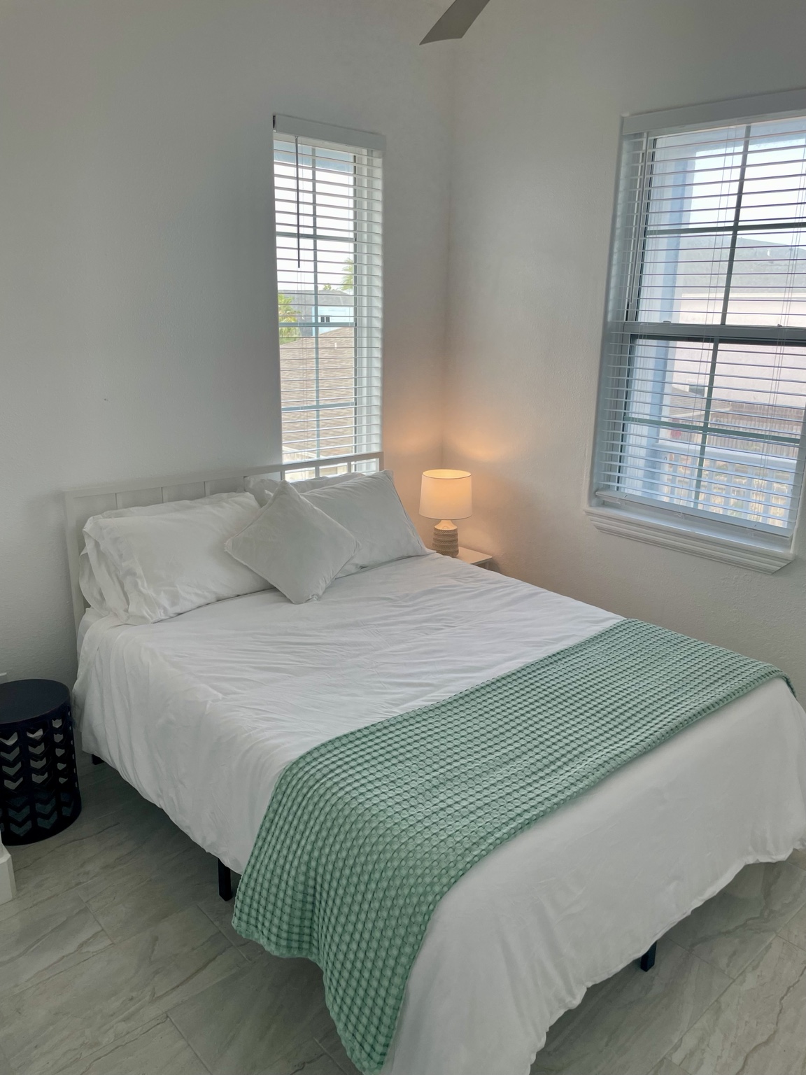 Second bedroom with a queen bed and soft green throw