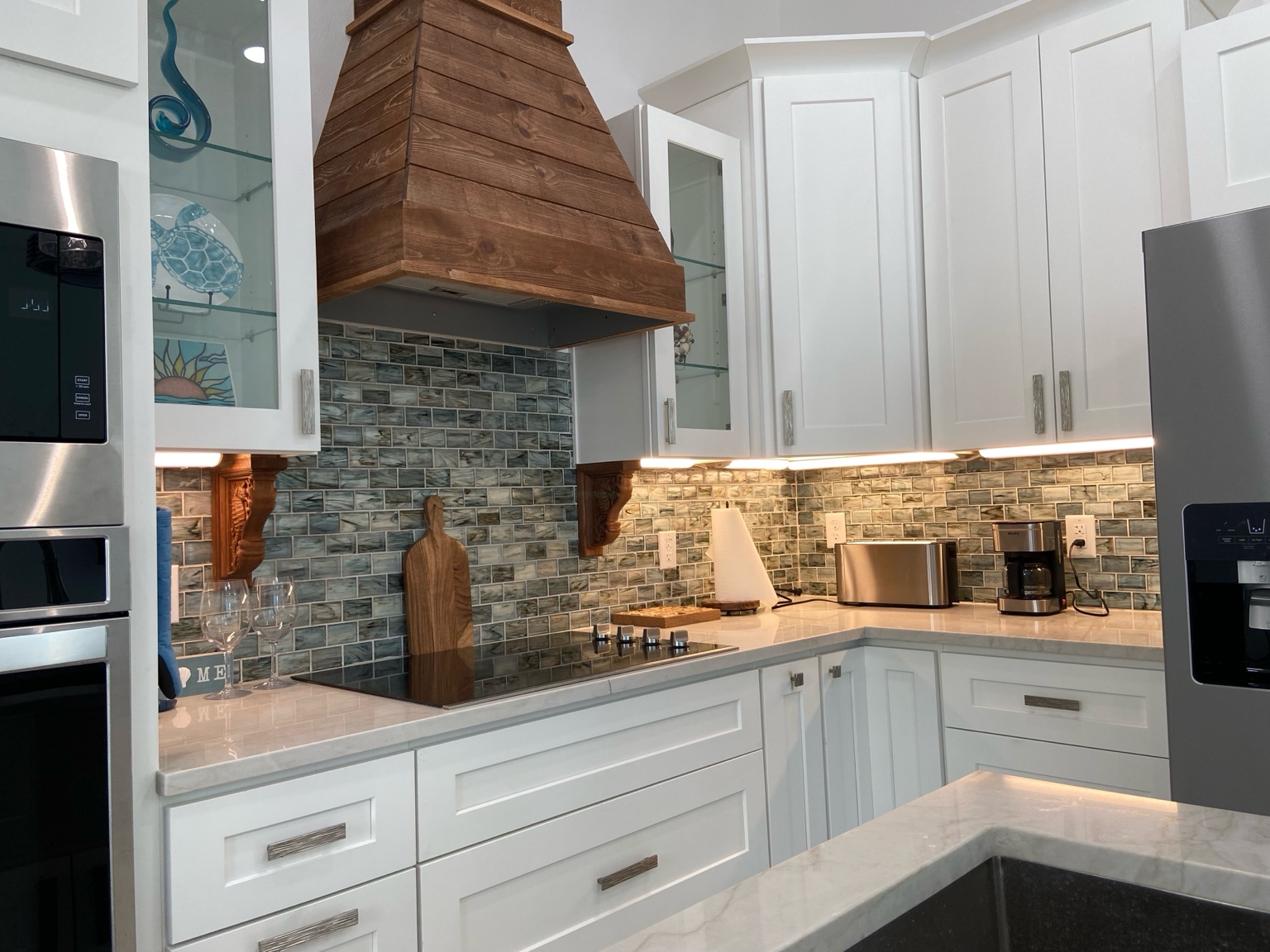 Full kitchen with white cabinets and a wood range hood